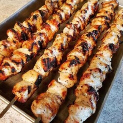 Grilled chicken skewers resting on metal pan