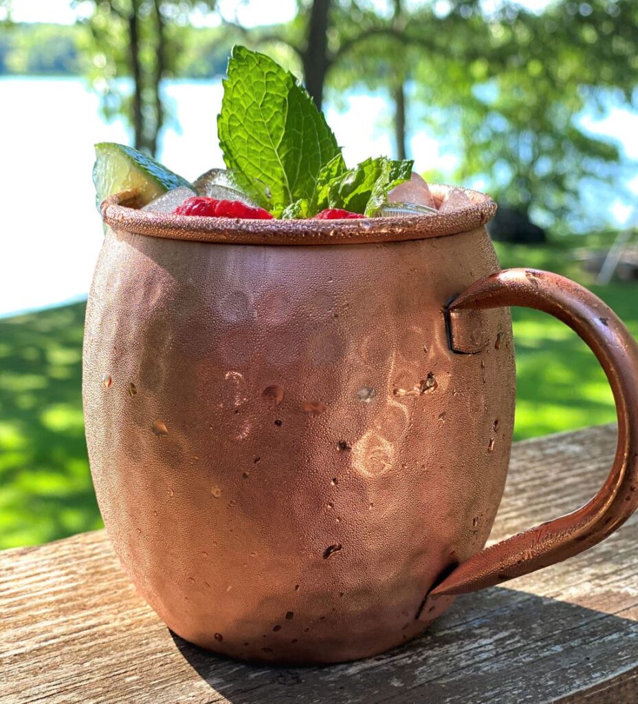 Raspberry Moscow mule in copper mug with summer background
